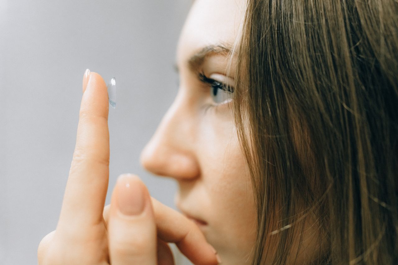 Crafting Captivating Headlines: Your awesome post title goes here A young woman focuses intently as she applies a contact lens, close-up shot highlighting her eye and careful fingers.